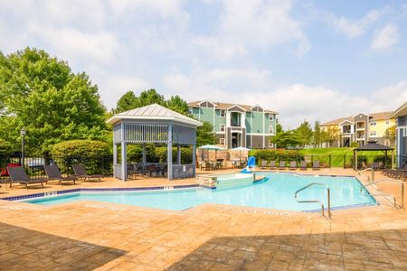 The pool area at our apartments for rent near Penn State, featuring beach chairs, umbrellas, and a clubhouse.