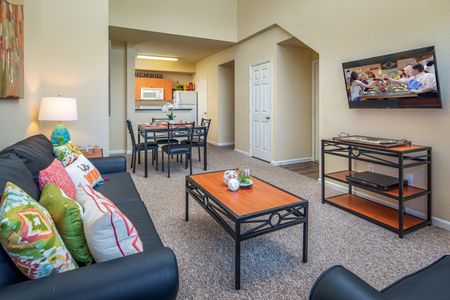 Model living room at our student living apartments in Orlando, featuring a couch, desk, and carpeted flooring.