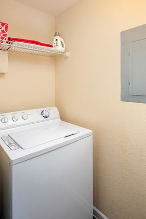 Laundry room at our apartments for rent in Orlando, featuring a rack for storage and a washing machine.