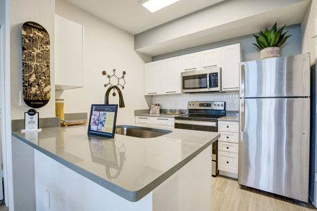 Model kitchen at our student housing in Orlando, featuring wood grain floor paneling and stainless steel appliances.