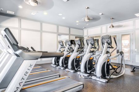 The fitness center at our apartments for rent near Penn State, featuring treadmills, exercise bikes, and ceiling fans.