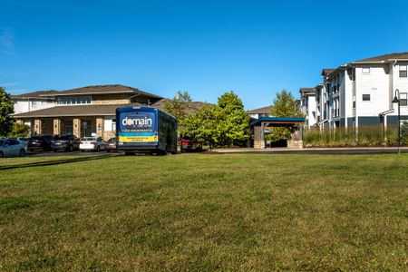 Photograph of the lawn at our apartments in Morgantown, featuring a student bus, cars, and a view of the apartment complex.