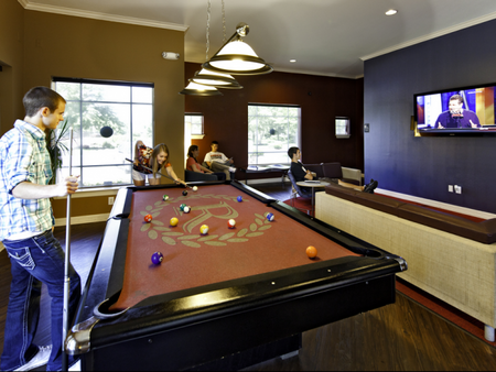 Residents playing pool and watching TV in the game room at The Reserve on West 31st