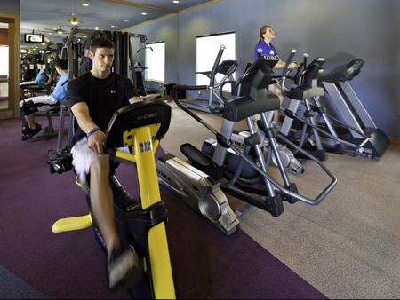 Two men and a women using a weight machine, a recumbent bike, and an elliptical in the fitness center at The Reserve on 31st
