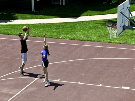 A man and a woman playing basketball on the full-length court at The Reserve on West 31st
