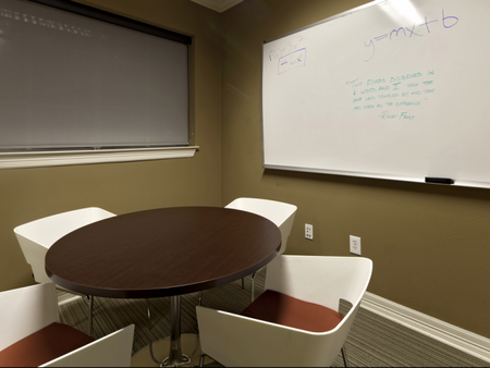A table, four chairs, and a white board in the study room at The Reserve on West 31st