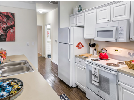 Model kitchen at our apartments in Tuscaloosa, featuring wood grain floor paneling and tan countertops.