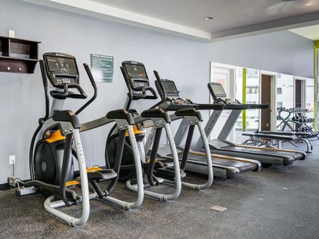 Fitness center at our apartments in St Louis, featuring cardio equipment and free weights.