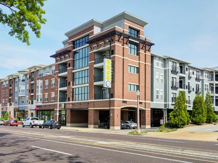 Photograph of the 3949 Lindell apartment building exterior during the day, featuring a city street, and nearby storefronts.