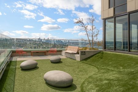 Rooftop balcony with grass and seating overlooking the Seattle skyline.