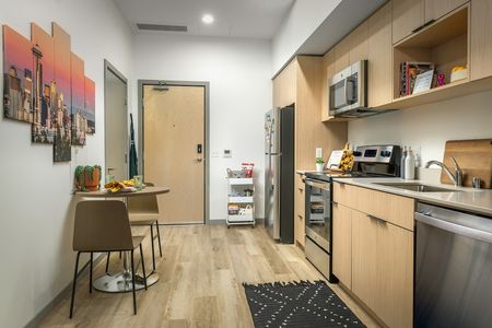 Model kitchen at our apartments in Seattle, featuring wood grain floor paneling and stainless steel appliances.