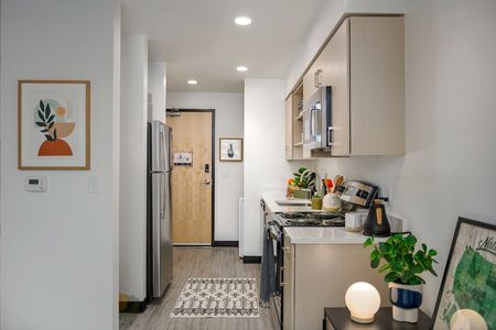 Model apartment kitchen with light wood cabinets and stainless steel appliances