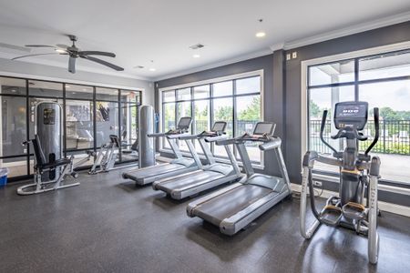 Fitness center treadmills and ellipticals looking out through large windows looking out at the community