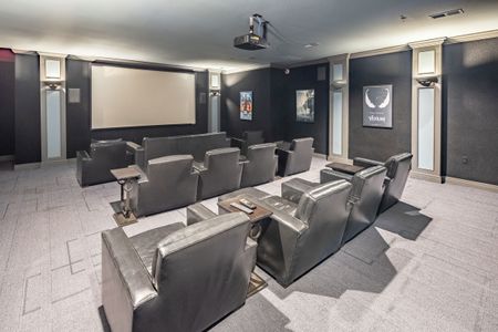 Movie theatre room with large screen, projector, and theatre-style seating for residents to use