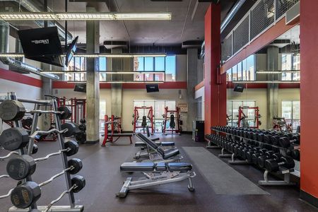 First floor of the fitness center with free weights, benches, and a large mirrored wall