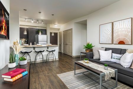 Model apartment with an open concept kitchen and living room with hardwood style flooring and white painted walls