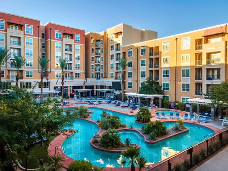 Picture of the building exterior with apartments all facing the pool deck which includes the lazy river