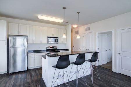 Model kitchen at our apartments for rent in Storrs, CT, featuring wood grain floor paneling and black counter tops.