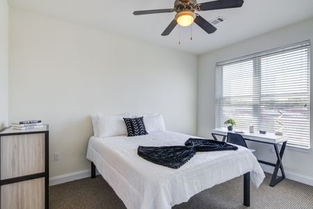Model bedroom at our apartments for rent in Storrs, CT, featuring carpeted flooring and windows with blinds.