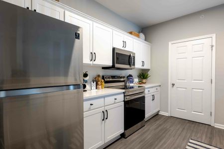 Model apartment kitchen with white cabinetry, white countertops, and stainless steel appliances