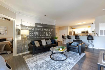 Model apartment living room with gray hardwood style flooring and a mural of Greenville, NC