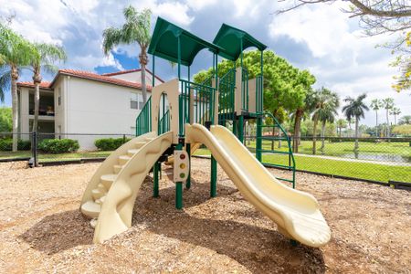 The play structure at our apartments in Palm Beach Gardens, featuring a wood chip playground and palm trees.