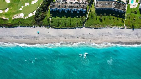 Aerial photograph of the Mira Flores Apartments in Palm Beach, Florida, featuring green laws, the beach, and turquoise water.