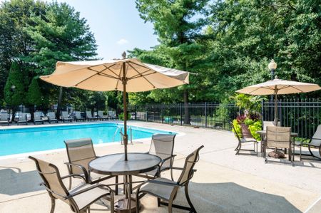The pool area at our apartments for rent in Germantown, MD, featuring beach chairs, tables, and umbrellas.mbrellas.