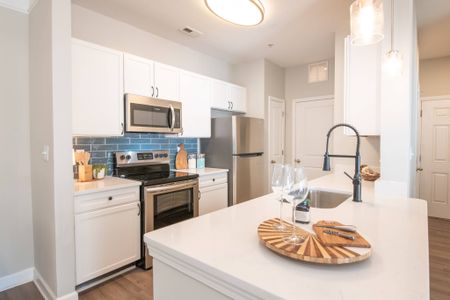 Model kitchen at our apartments for rent in Mooresville, featuring stainless steel appliances and white countertops.