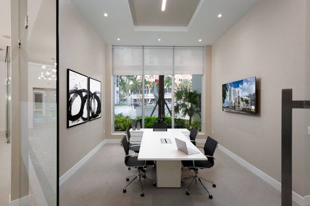 Conference room at our apartments in Fort Lauderdale, featuring a white conference table, black office chairs, and modern art.