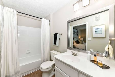 Renovated bathroom in an apartment for rent in Acworth, GA. White tiled shower, toile.t, tub, and vanity