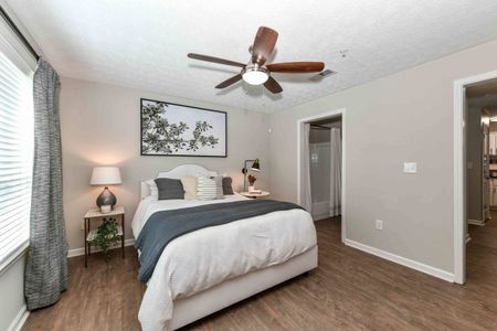 Renovated bedroom with large window, ceiling fan, and bathroom in an apartment for rent in Acworth, GA.