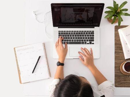 person on laptop with note pad