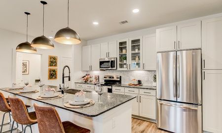 Beautiful kitchen with white cabinetry and an island with a granite countertop inside a Grapevine apartment for rent.