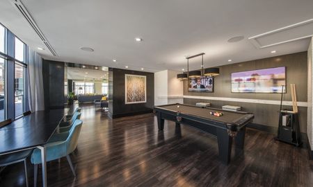 Entertainment room and lounge at our apartments in Arlington, featuring wood grain floor paneling and a billiards table.
