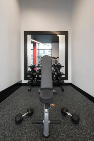 Fitness CenterFitness center at our apartments for rent in Arlington, featuring a bench press stand with free weights.