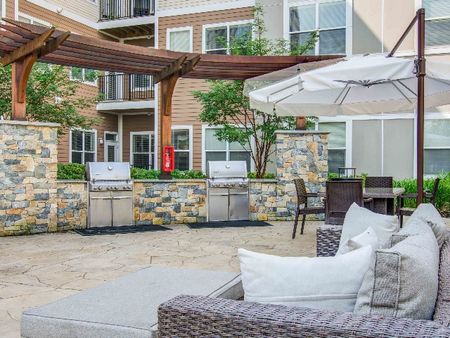 Outdoor lounge at our apartments in Wakefield, featuring outdoor couches, an umbrella, and a grill station.