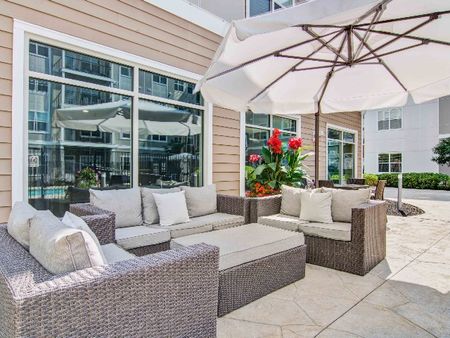 Outdoor lounge at our apartments in Wakefield, featuring outdoor couches, an umbrella, and a view of the clubhouse.