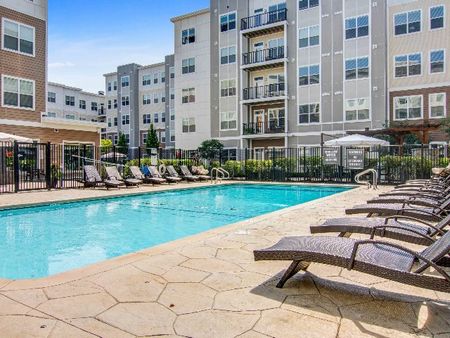 The pool area at our apartments in Wakefield, featuring beach chairs, umbrellas, and a shade structure.