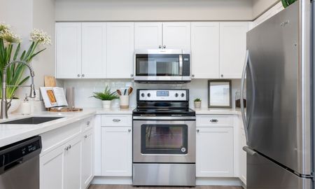 Model kitchen at our apartments for rent in Pompano Beach, FL, featuring white countertops and stainless steel appliances.
