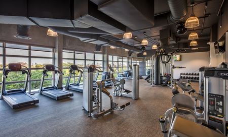 The fitness center at our apartments in Miami, featuring treadmills, elliptical bikes, weights, exercise machines, and more.