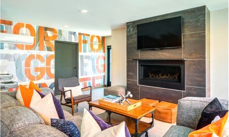 Resident lounge at our apartments for rent in Washington DC, featuring a fireplace, a TV, and colorful wall paper.