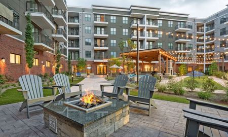 Outdoor lounge at our apartments for rent in Sandy Springs, featuring a fire pit, chairs, and a view of the apartments.