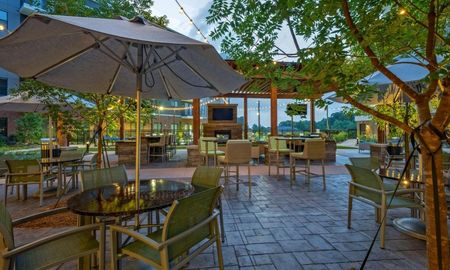 Outdoor lounge at our apartments for rent in Sandy Springs, featuring a outdoor seating, umbrellas, and a TV.