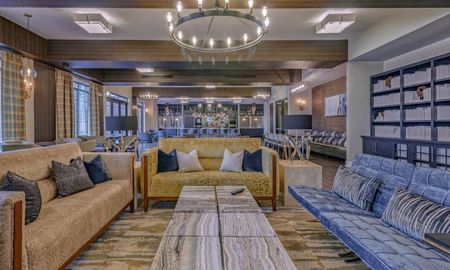 Lounge at our apartments in Sandy Springs, featuring carpeted floors, couches, and books on shelves.
