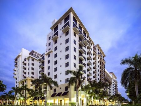 Photograph of the exterior of The Mark at Cityscape apartments in Boca Raton, featuring palms, lights, and the night sky.