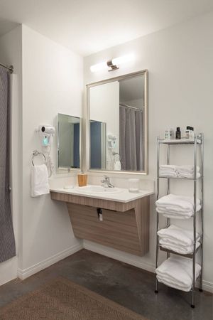 Model bathroom at our apartments in Kenmore, featuring stacks of towels, a large mirror, and white countertop.
