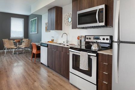 A modern kitchen with wood cabinetry and stainless steel appliances in a luxury apartment near Seattle.