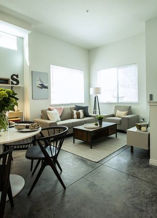 Interior view of a living room with a grey sofa and a kitchen with white cabinetry in a Kenmore WA apartment.