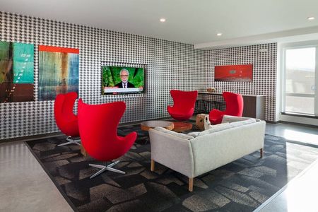 Community lounge with red chairs and a television in Kenmore apartments.